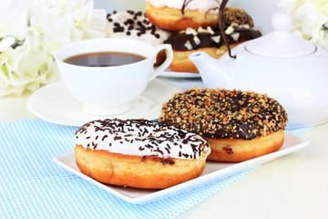 Sweet donuts with cup of tea on table close-up