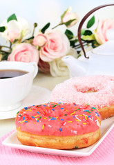 Sweet donuts with cup of tea on table close-up