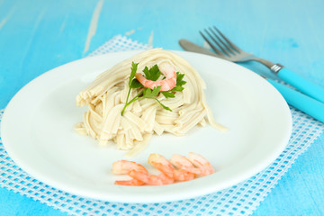 Pasta with shrimps on white plate, on wooden background