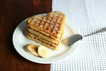 Sweet Belgium waffles with banana, on wooden table background