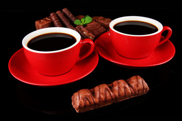 Red cups of strong coffee and chocolate bars isolated on black