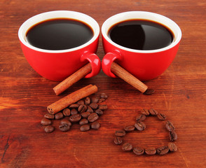 Red cups of strong coffee and coffee beans on wooden background