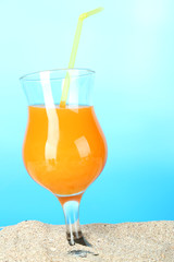 Beach cocktail in sand on blue background