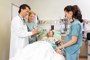 Fototapeta na wymiar Medical Team Examining Patient In Hospital