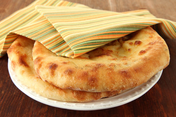 Pita breads in plate with napkin on wooden background