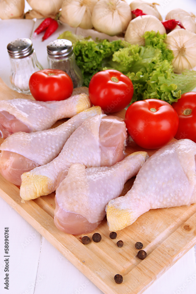 Wall mural raw chicken legs on wooden board close up