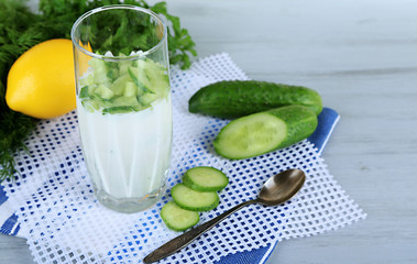 Cucumber yogurt in glass, on color napkin, on wooden