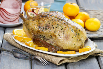 Roasted duck with oranges on wooden table