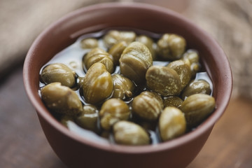 Pickled capers in ceramic bowl, close-up, studio shot