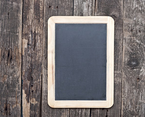 Grunge small blackboard hanging on wooden wall as a background f