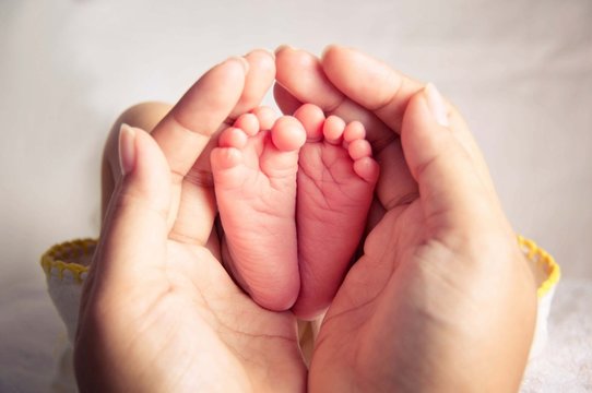 mother hands holding small baby's feet