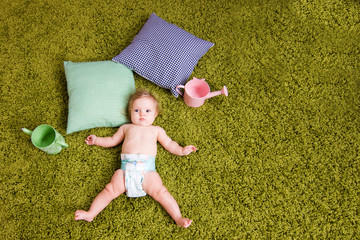 Little baby lies on green carpet