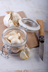 Knoblauch im Glas mit Holzmesser