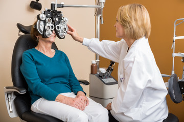 Optician Using Phoropter To Examine Woman's Eyes