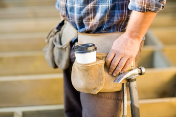 Disposable Coffee Cup And Hammer On Carpenter's Tool Belt