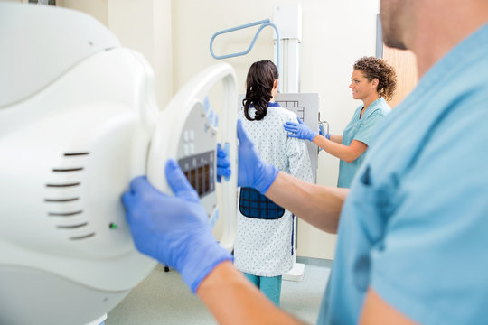 Nurse Adjusting Xray Machine In Examination Room