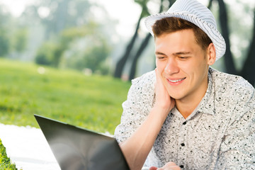 young man working in the park with a laptop