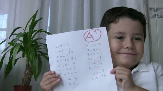 Child showing exm paper with A+