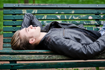 Attractive blue eyed, blond young man laying on park bench