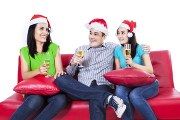 Fototapeta na wymiar Three teenagers in santa hat drinking wine