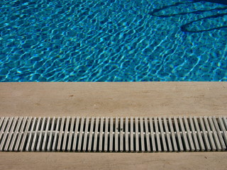 Beckenrand und Abfluss eines Swimmingpool in Beige und Naturfarben im Sommer bei Sonnenschein im...