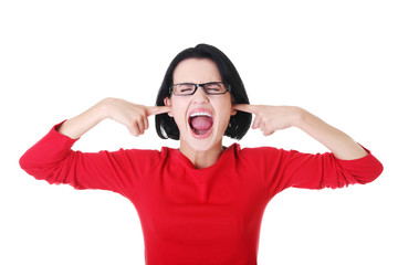 Attractive woman in eyeglasses puts her finger into ears.