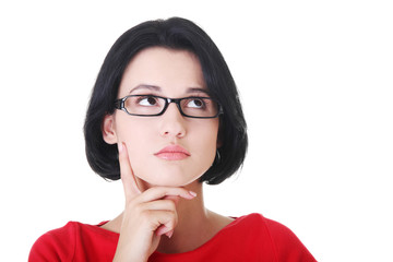 Attractive woman in eyeglasses is looking up and thinking.