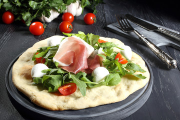 pizza bianca prosciutto e rucola sfondo grigio