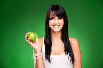 beautiful brunette woman with green apple on green background