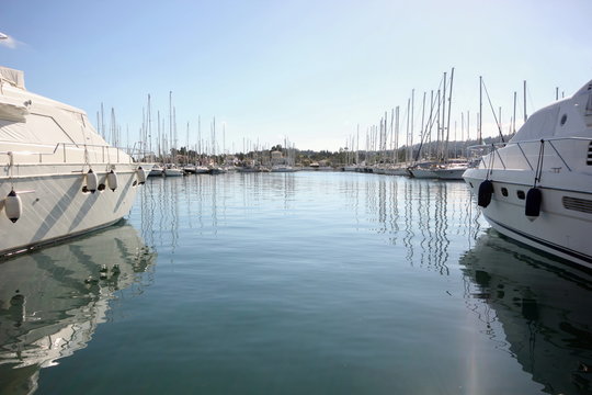 large motor boats and yachts with masts in the calm waters of a marina