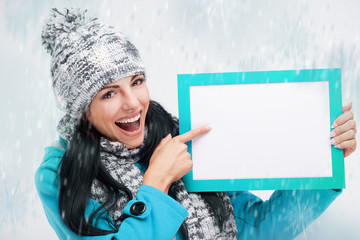 smiling girl pointing at a blank board and around snowing