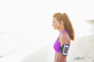 Portrait of fitness young woman in headphones on beach 