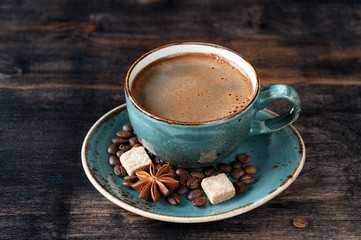 Cup of coffee with sugar and spices on dark wooden background