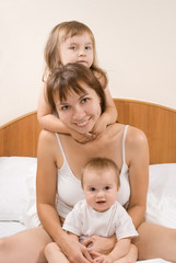 Mother and children playing and smiling on the bed at home