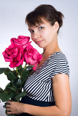 Young woman with three gorgeous pink roses on gray background