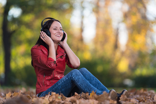 Girl Listening To Music On Autumn Leaves