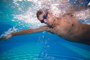Young man swimming the front crawl in a pool - underwater shot