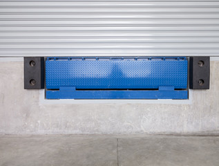 Dock leveler or height adjustable platform outside warehouse or industrial building. Used as bridge...