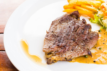 beef steak on white dish with salad and french fries
