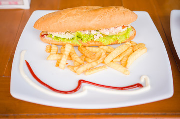 Sandwich with chicken and french fries on plate in beach restaur