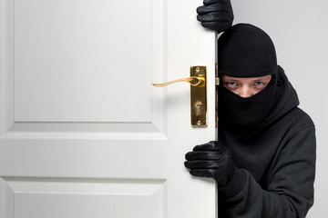 Burglar sneaking in a open house door