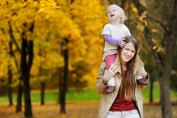 Young mother and toddler girl have fun at autumn