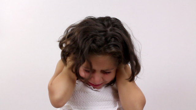Young girl pouts and protests and covers his ears.