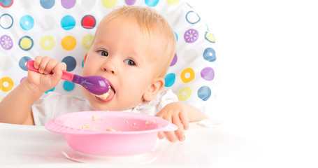 Fototapeta na wymiar happy baby child eats itself with a spoon
