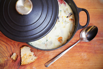 Clam chowder with sausage and potatoes in iron casserole