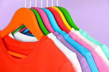 Different shirts on colorful hangers on purple background