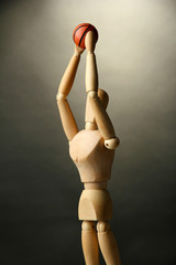 Wooden mannequin with basketball ball on grey background