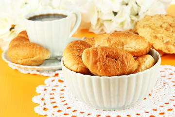 Tasty croissants and cup of coffee on table close-up