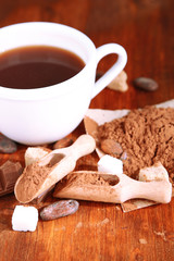 Cocoa in cup and coca powder on wooden table