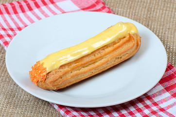 Eclair with a cream on a plate
